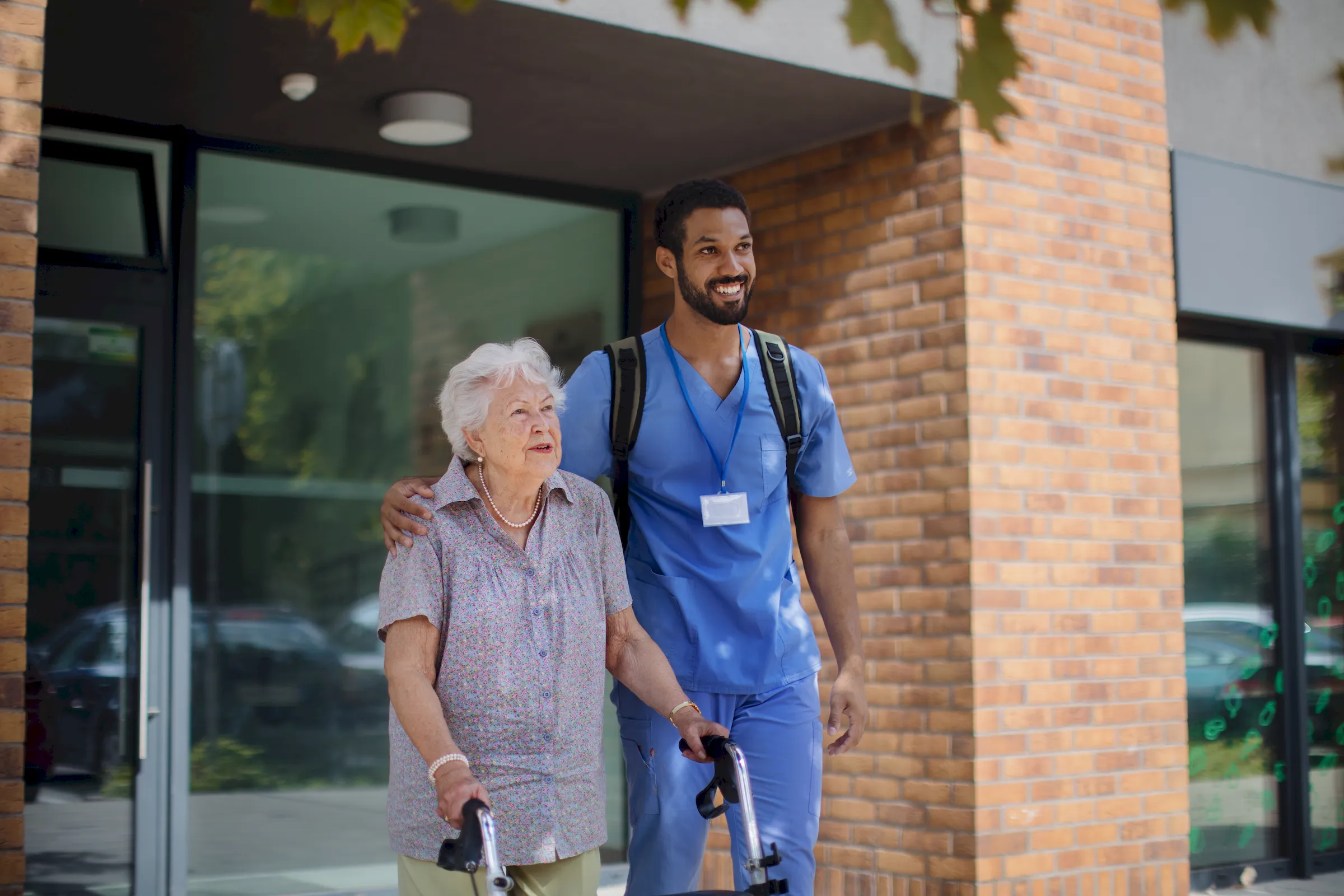 A carer walking with an older resident who is using a walking stick.